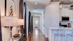 A modern kitchen with white cabinets, a black microwave, and a glass bar counter. - Updated 3BR Mid-City home with private pool. Steps to streetcar, near FQ & parade route. (New Orleans)