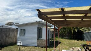 Une petite maison de plain-pied dotée d’un patio couvert.