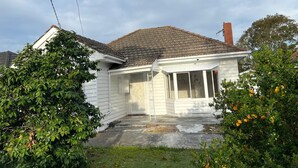 Une maison de plain-pied avec un toit en pente, un porche à l’avant et une cheminée bien visible.