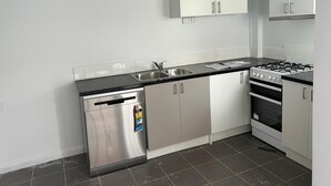 Une cuisine moderne dotée d’appareils électroménagers en acier inoxydable, d’un lave-vaisselle et de meubles blancs.