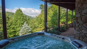 Een bubbelbad met uitzicht op een bos en bergen.