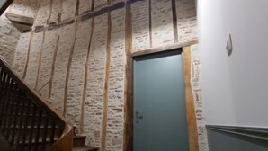 Una scala con gradini in legno che conduce a una porta, un lampadario a soffitto e un muro in pietra.