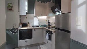 Una cucina compatta con mobili bianchi, un frigorifero in acciaio inossidabile, un forno a microonde e un lavandino.