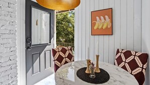 A room with a marble table, patterned cushions, a framed artwork, and a door leading outside. - Field of Dreams (Atlanta)