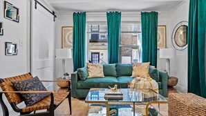 A living room with a green sofa, a glass coffee table, and a brown leather armchair. - Field of Dreams (Atlanta)