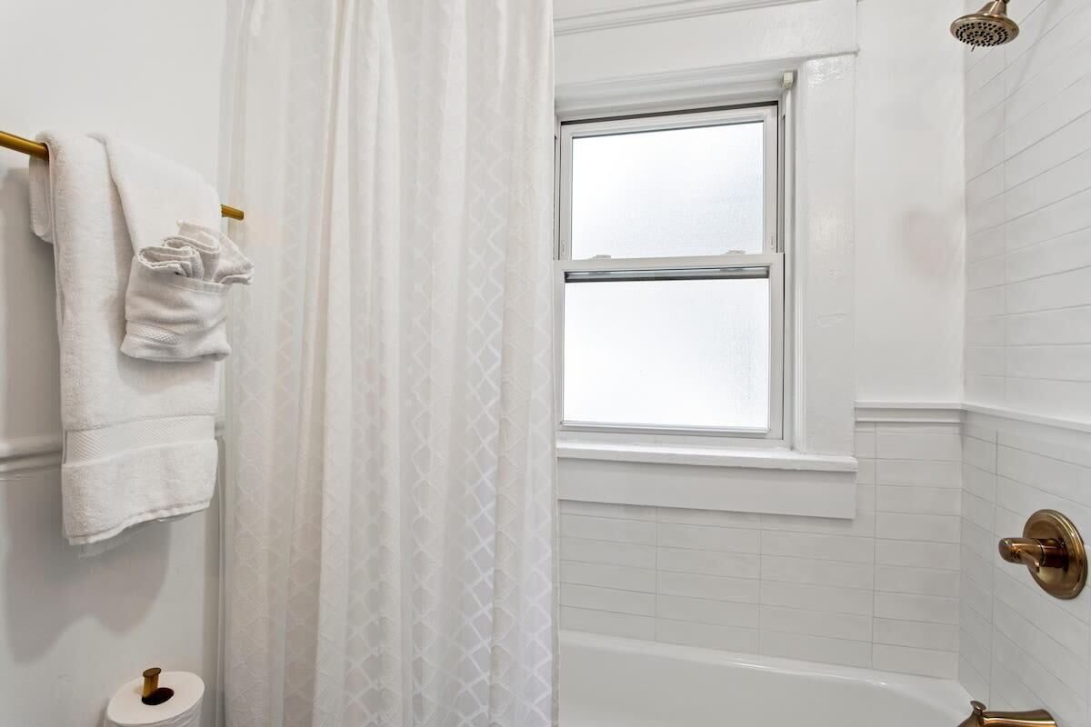 Une salle de bain avec une baignoire, un porte-rouleau de papier toilette et une fenêtre.