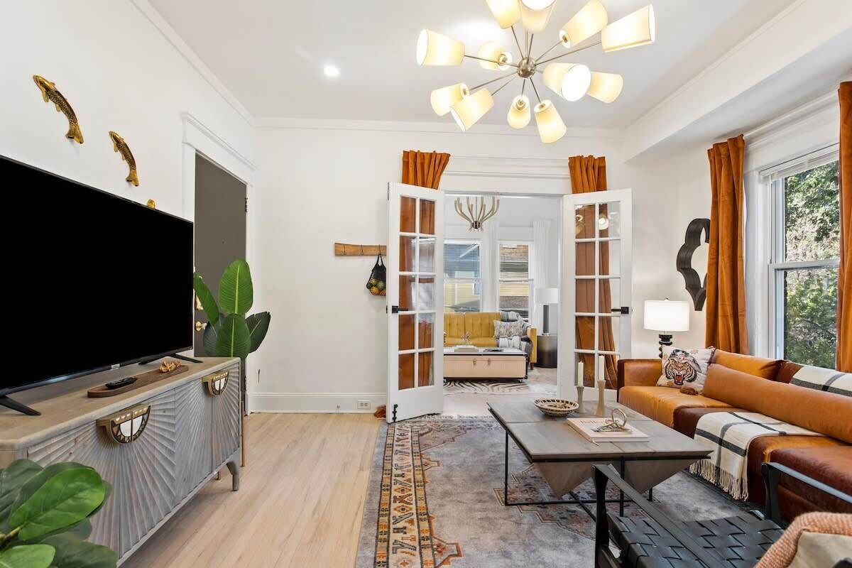 Una sala de estar con televisor de pantalla plana, una mesa de centro, un sofá y una araña.