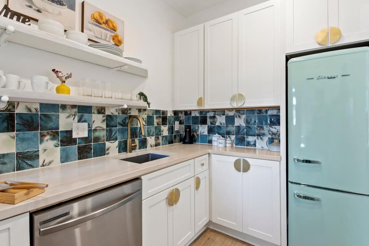 A kitchen with white cabinets, a blue refrigerator, and a tiled backsplash.