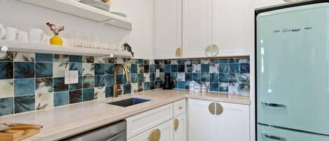 A kitchen with white cabinets, a blue refrigerator, and a tiled backsplash.