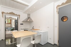 A modern kitchen with a wooden table, white chairs, a built-in oven, and a decorative mirror. - Fantastic 3 bedroom apartment in the heart of Florence (Firenze)