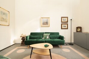 A room with a green sofa, a small round table, a lamp, and framed pictures on the wall. - Fantastic 3 bedroom apartment in the heart of Florence (Firenze)