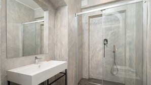 A modern bathroom with a white sink, a glass-enclosed shower, and a large mirror. - Fantastic 3 bedroom apartment in the heart of Florence (Firenze)