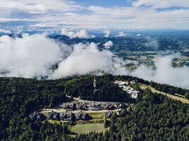 Un paisaje montañoso con un grupo de edificios rodeados de un bosque denso.