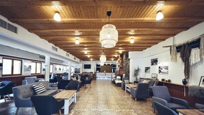 A spacious indoor area with wooden ceiling beams, multiple seating arrangements including sofas and chairs, and a central table. - Pohorje Village Wellbeing Resort – Family Apartments Bolfenk (Maribor)