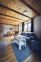 Un salón amplio con techo de madera, un sofá, una mesa de centro y una mesa de comedor con sillas.