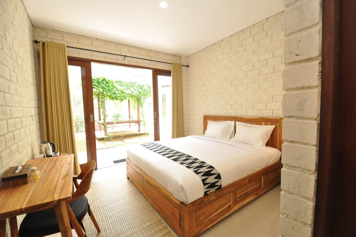 A bedroom with a wooden bed, a wooden desk, and a view of the outdoors.