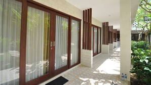 Un pasillo moderno de hotel con grandes puertas correderas de vidrio, piso de baldosas y pared de ladrillo.
