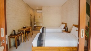 Una habitación con dos camas, un escritorio de madera, una silla, una mesita y un espejo.