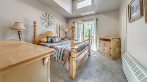 Een slaapkamer met een houten bed, nachtkastje, dressoir en een raam met gordijnen.