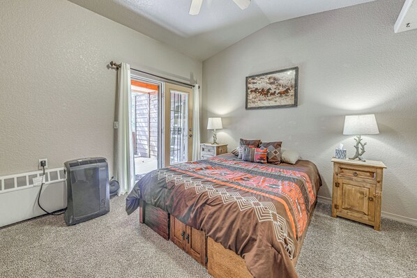 A bedroom with a bed, bedside lamps, a heater, and a door leading to a balcony.