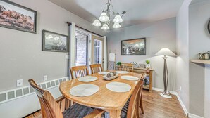 Een eethoek met een houten tafel en stoelen, een kroonluchter en ingelijste foto's aan de wanden.