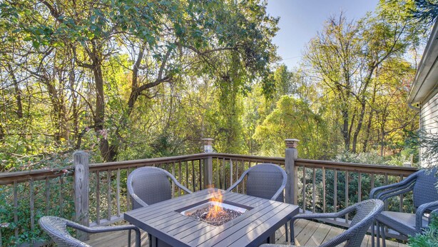 Una terrazza con un tavolo quadrato e quattro sedie, circondata da alberi.