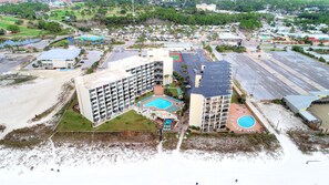 A multi-story hotel with a central courtyard pool, a smaller pool on the second floor, and a beachside location.