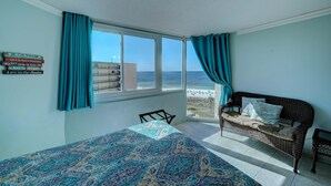 Una habitación con una cama, un sofá de mimbre y vista al mar.