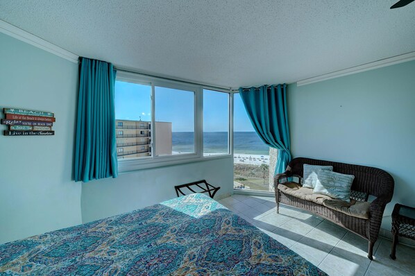 Une chambre avec un lit, un canapé en osier et vue sur la plage.