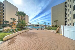 Un hôtel doté d’une piscine, de palmiers et d’un panneau indicateur.