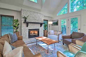 Cozy living room with a fireplace, comfortable seating, and a large window offering a view of the outdoors.