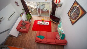 A modern living room with a red sofa, a TV, and a dining area with a red rug. - Special 3 Bedroom Townhouse With Parking in Bristol (Bristol)
