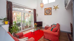 A living room with a red sofa, a glass coffee table, a TV, and a star decoration on the wall. - Special 3 Bedroom Townhouse With Parking in Bristol (Bristol)