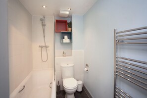 A modern bathroom with a bathtub, toilet, and shower.