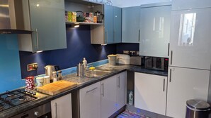 A modern kitchen with stainless steel appliances, white and light blue cabinets, and a wooden countertop. - Special 3 Bedroom Townhouse With Parking in Bristol (Bristol)