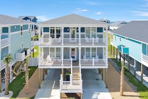 A multi-story beachfront building with balconies, outdoor seating, and a covered walkway.