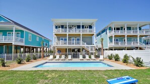 Un edificio de dos pisos con piscina, barandillas blancas y una combinación de colores azul y blanco.