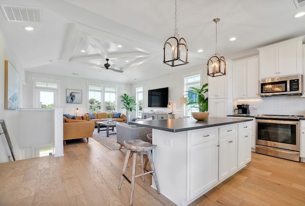 A spacious kitchen with white cabinetry, a central island, stainless steel appliances, and pendant lighting.