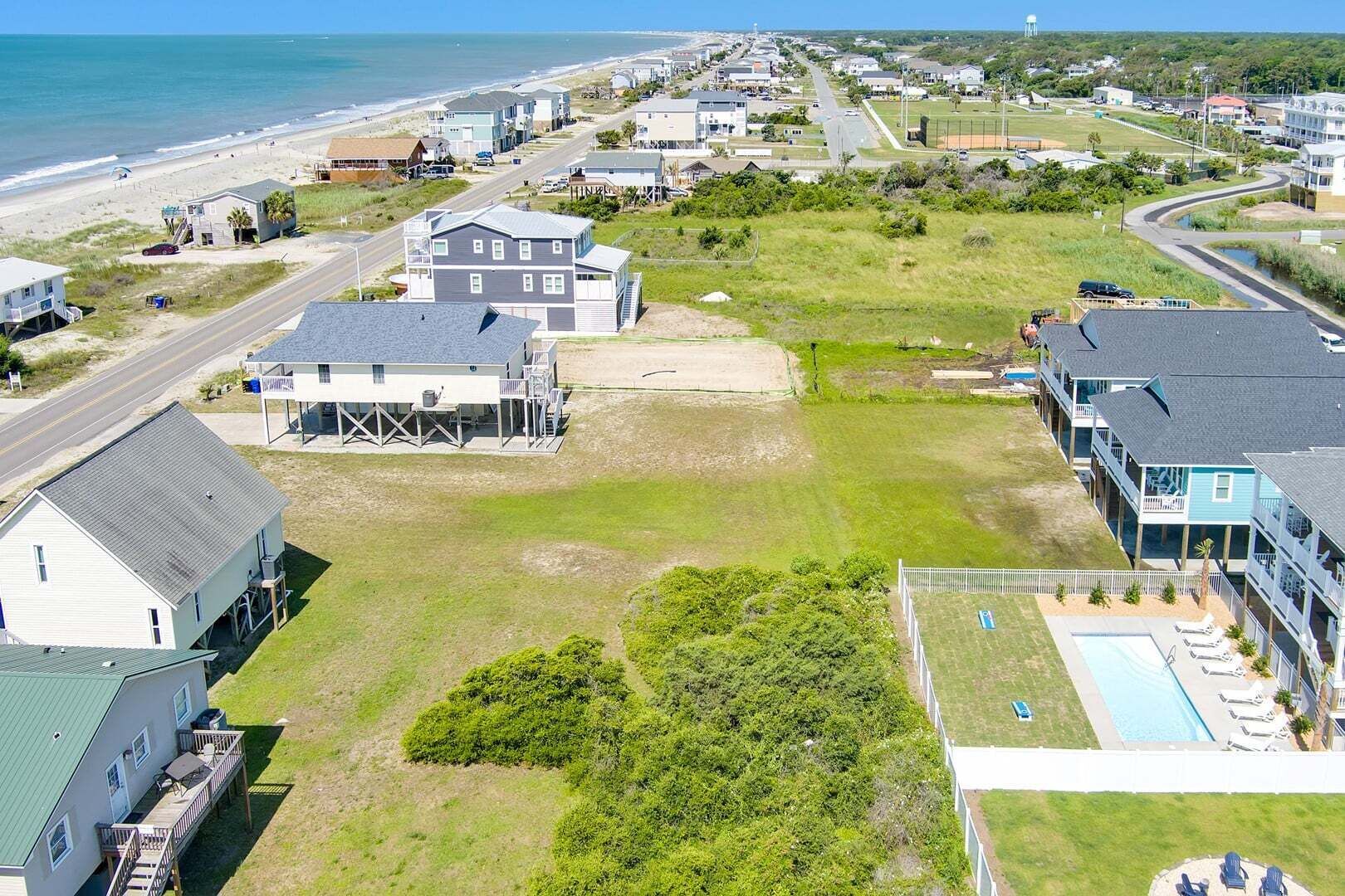 Vista aerea di una zona costiera con case, una spiaggia e una piscina.