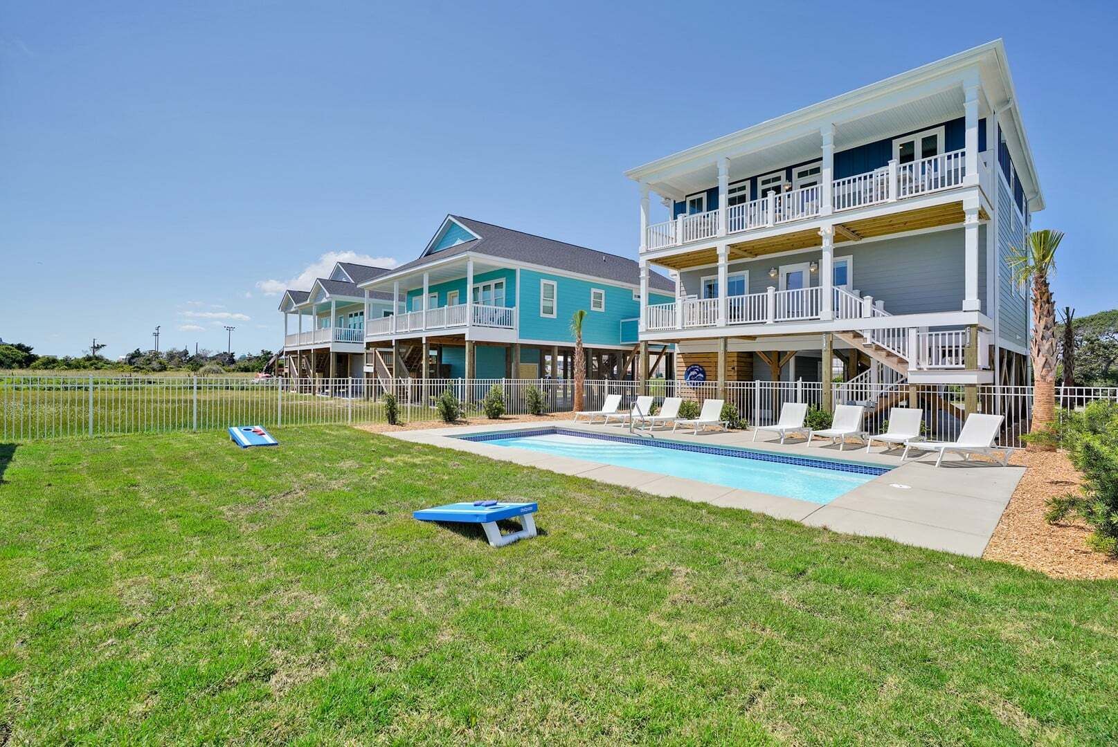 Une maison à deux étages avec une piscine, une cour clôturée et un ciel dégagé.