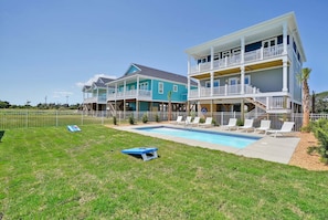 A two-story house with a swimming pool, a fenced yard, and a clear sky.