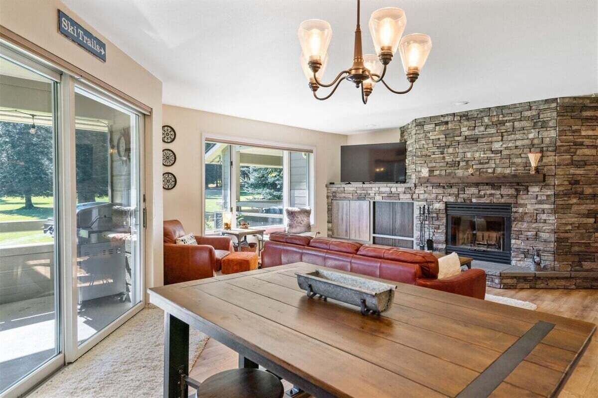 Amplia sala de estar con chimenea de piedra, asientos de cuero, una mesa de comedor de madera y una gran pantalla de televisión.