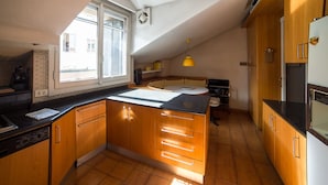 A kitchen with wooden cabinets, a black countertop, and a window with blinds. - HbHall - Duomo Suite 7 Apartment (Milan)