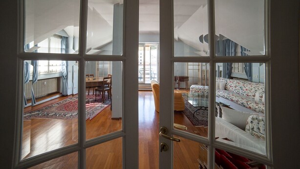 A spacious living area with a high ceiling, a dining table, and a sofa. - HbHall - Duomo Suite 7 Apartment (Milan)