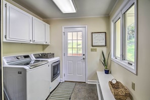 Convenient laundry facilities with washer and dryer, a small potted plant, and a laundry guide on the wall.
