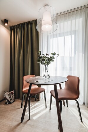 Un comedor moderno con una mesa redonda, dos sillas, un florero con plantas y una lámpara colgante.