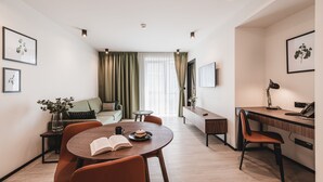 A modern living room with a round dining table, orange chairs, a sofa, a coffee table, and a TV on the wall. - Apartamenty Sowa Bydgoszcz (Bydgoszcz)