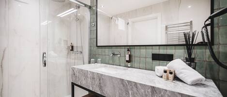 A modern bathroom with a glass-enclosed shower, a marble sink, and a large mirror.