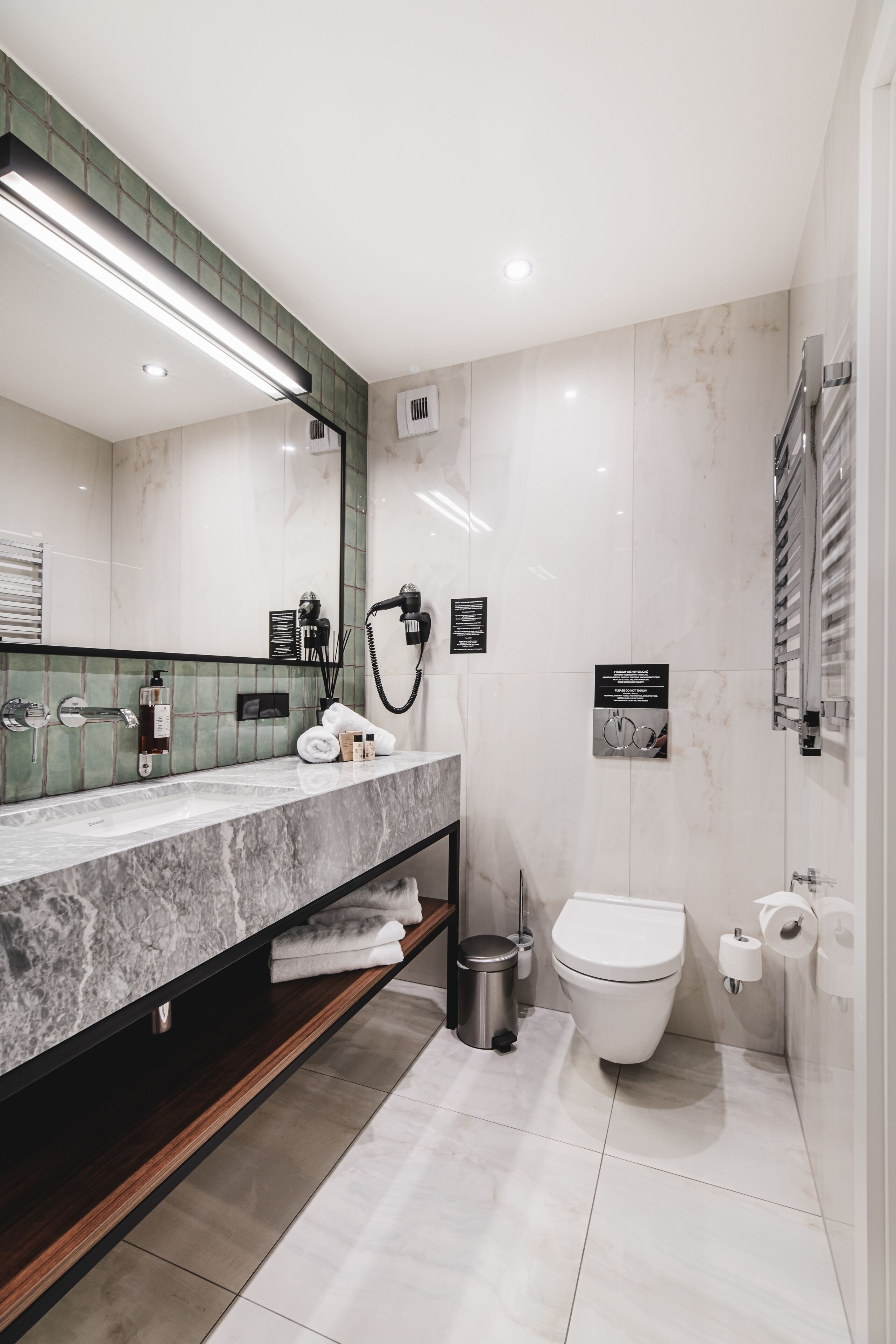 A modern bathroom with a marble vanity, a toilet, and a large mirror.