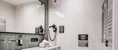 A modern bathroom with a marble vanity, a toilet, and a large mirror.